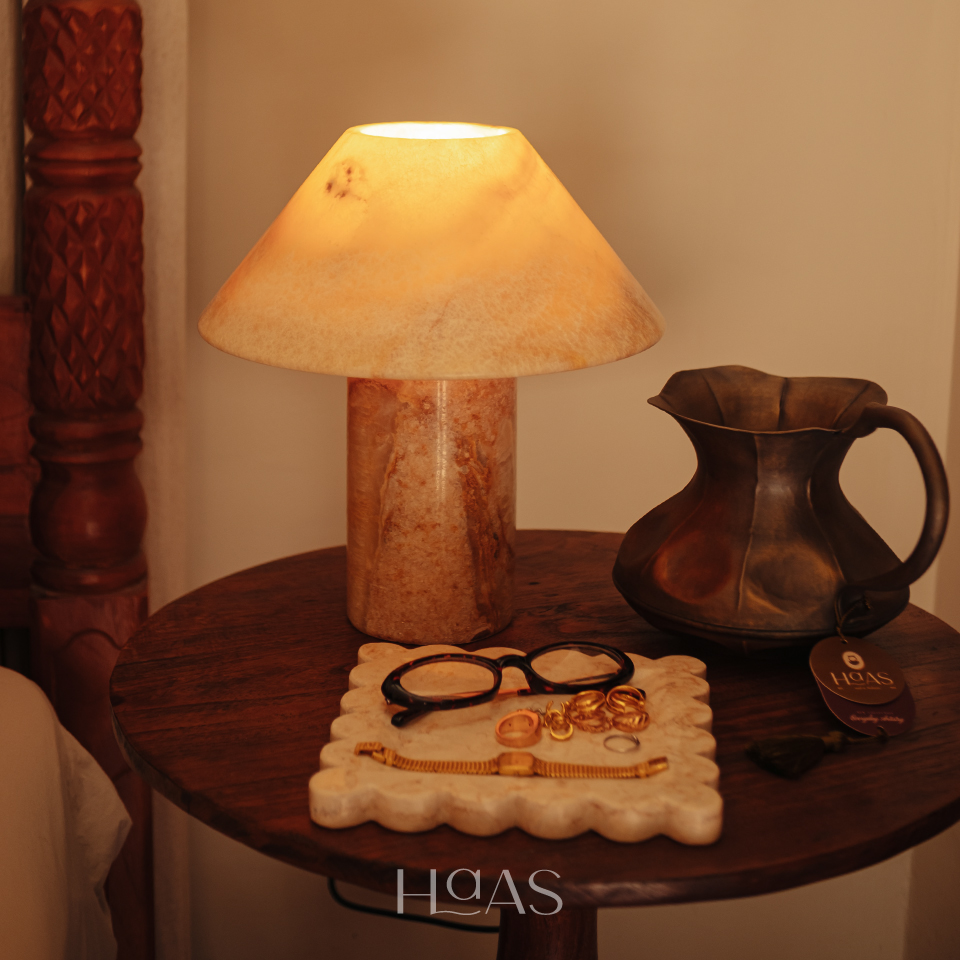 BHUMI table lamp lit on a side table with a scalloped tray and glasses