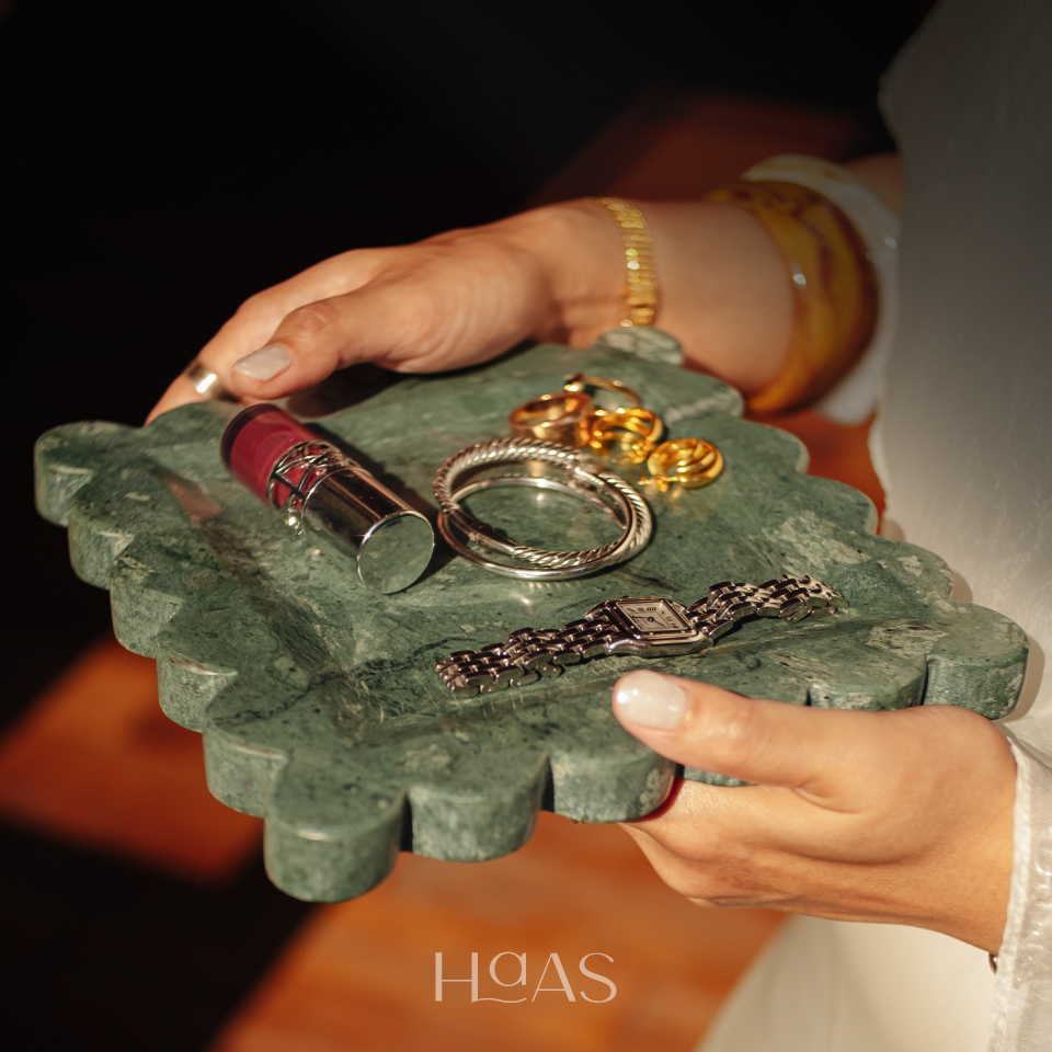 OMBAK green marble tray held in hands, styled with rings and a lipstick
