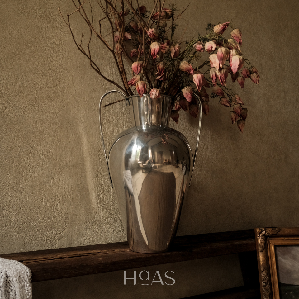 WANGSA chrome aluminium vase holding dried pink blooms on a console
