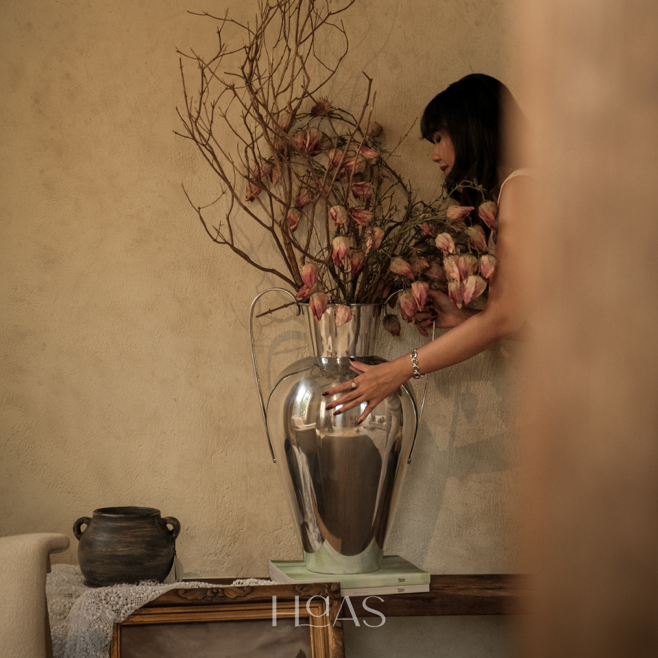 Woman arranging dried blooms in the tall WANGSA chrome aluminium vase