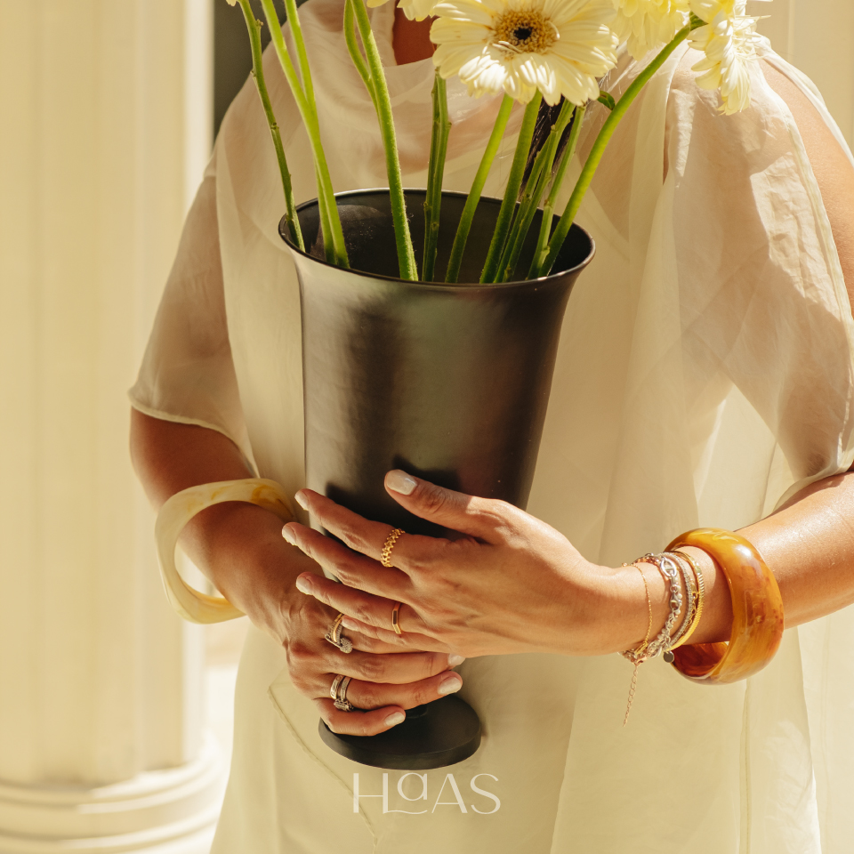 Hands holding the PILAR brass vessel and a bouquet to show its scale and flared shape